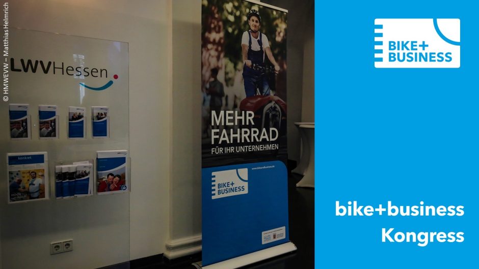 Auf der rechten Seite ist der Text "bike+business Kongress" und das logo von bike+business auf blauen Hintergrund zu sehen. Daneben sieht man einen Aufsteller mit einem Fahrrad drauf.